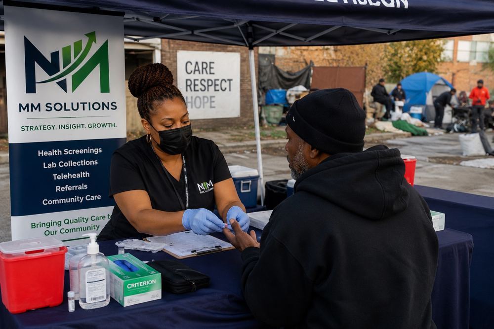 MM Solutions staff member assisting a patient at a mobile outreach tent on the street